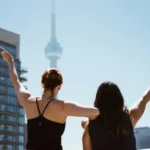 Deux expatriées brandissant des drapeaux canadiens devant la tour CN à Toronto